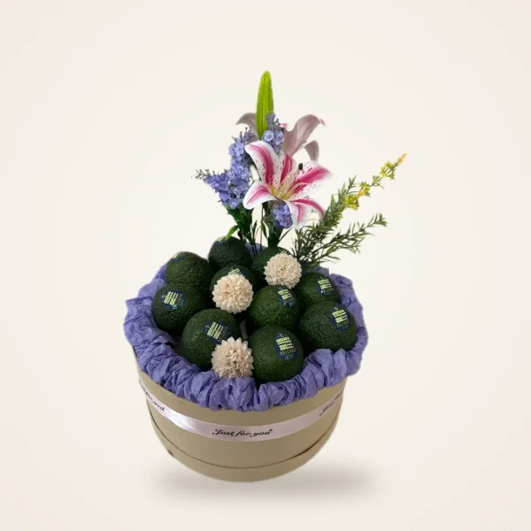 Avocado & Lily Flower Arrangement - avocados with lily and floral stems in a round hatbox