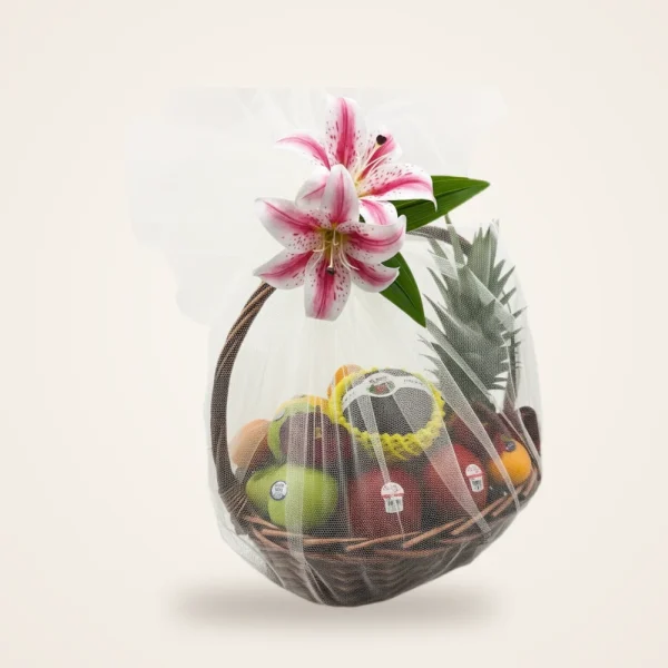 Clear-Wrapped Lily Fruit Basket - mixed fruit with a pink lily in a clear-wrapped woven basket