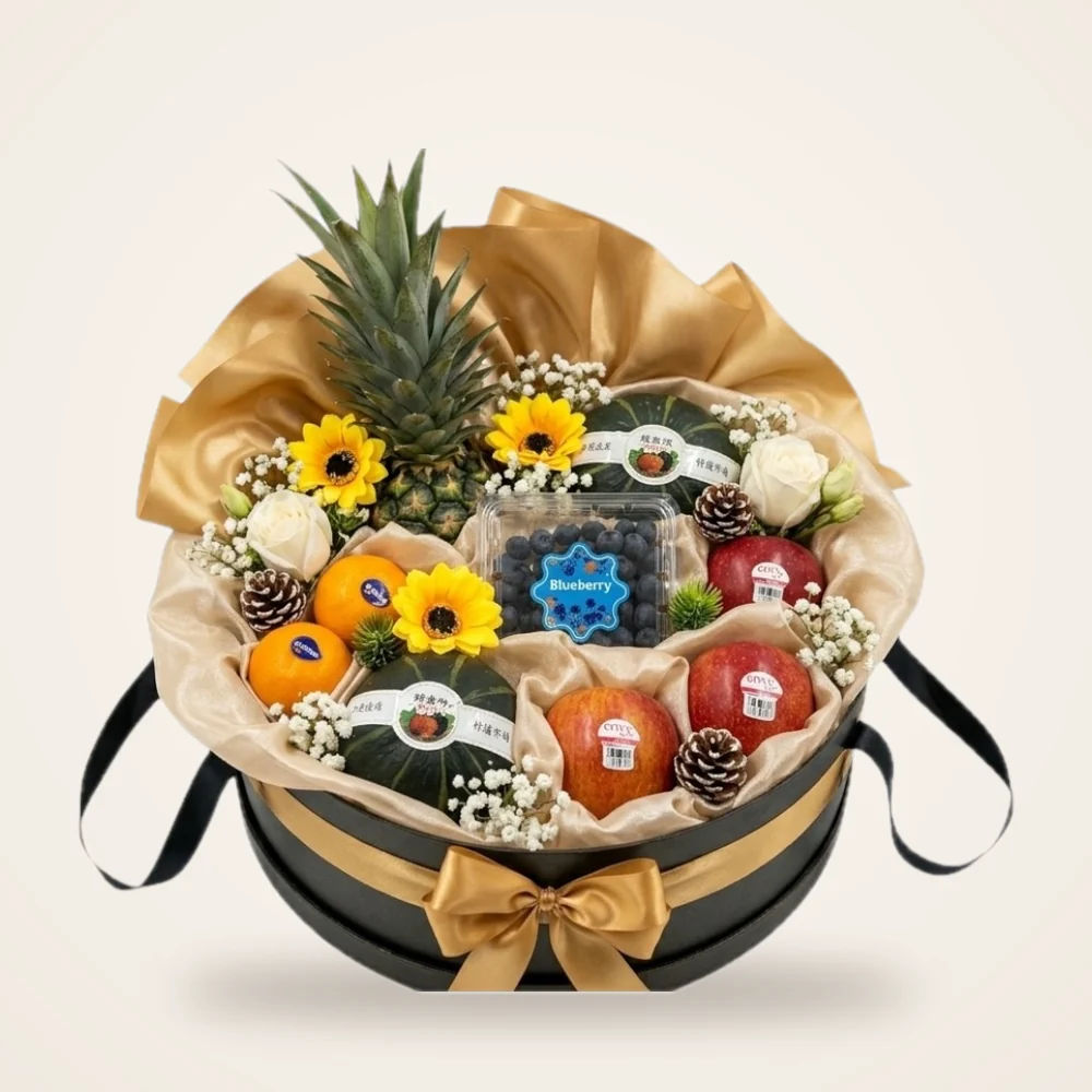 Gold Ribbon Hatbox Fruit Basket - pineapple, blueberries, pumpkin, oranges and sunflowers in a black hatbox with a gold bow